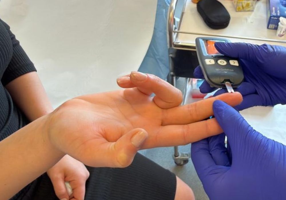 Medicul măsoară glicemia pacientului cu ajutorul unui glucometru, folosind o picătură de sânge prelevată din deget.